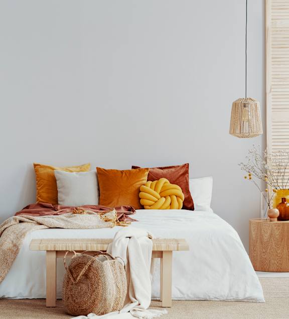 A bedroom with a bed, pillows, and a vase of flowers.
