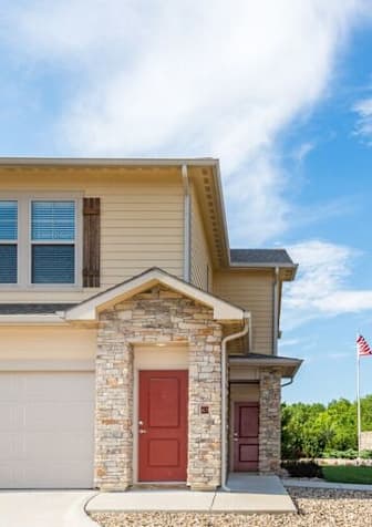 A house with a red door and a flag on the lawn.