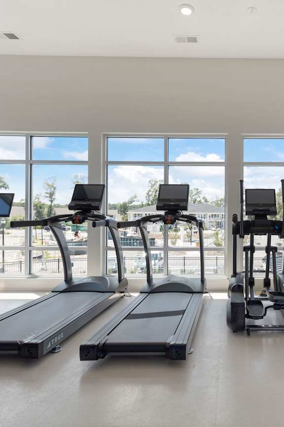 a workout room with treadmills and a tv