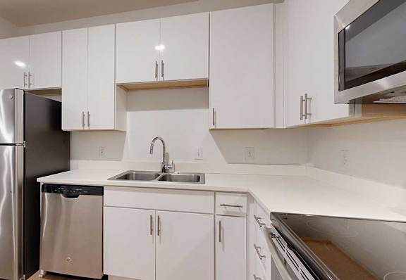 a kitchen with white cabinets and a stainless steel refrigerator next to a stainless steel sink