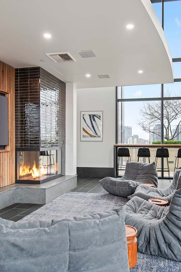 A modern living room with a grey bean bag chair and a flat screen TV mounted on a wooden wall.