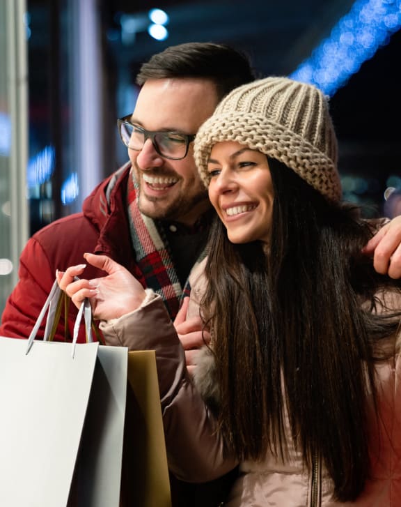 a man and a woman standing in a store window with shopping bags