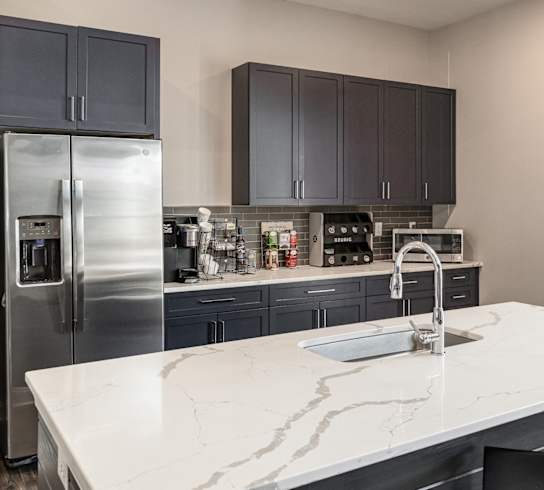 a kitchen with a marble counter top and a stainless steel refrigerator