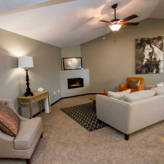 A living room with a beige couch, a chair, a lamp, a fireplace, and a fireplace
