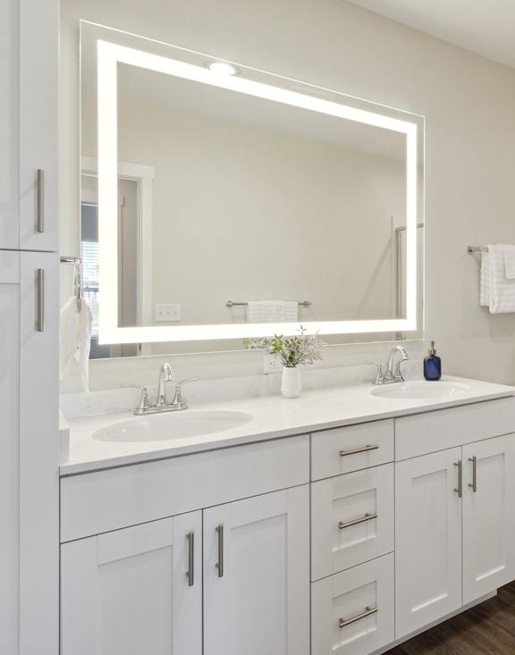 A white bathroom with a sink, mirror, toilet, and shower.