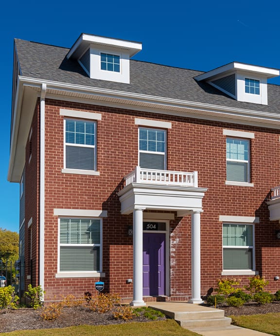a red brick house with purple doors and a black fence