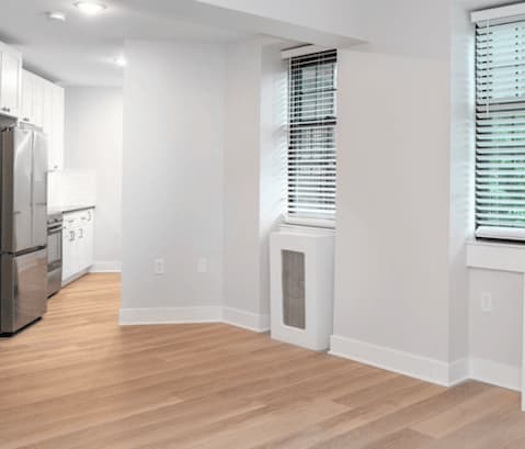 a living room and kitchen with white walls and wood floors