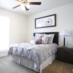 a bed with a grey comfortor in a white room