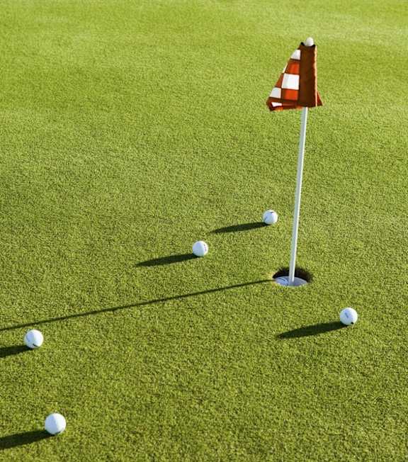 A golf course with a red and white flag on the green.