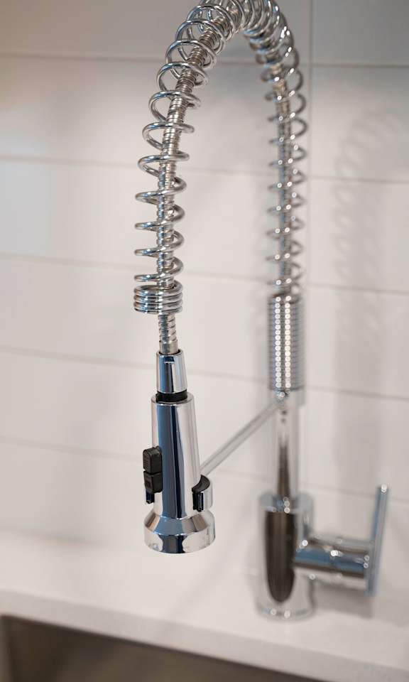 A chrome faucet with a hose attached to it.
