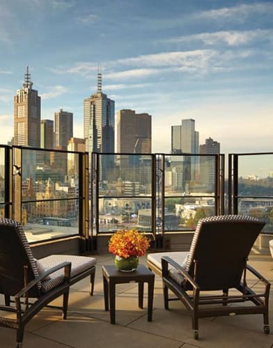 a balcony with two chairs and a table and a view of a city