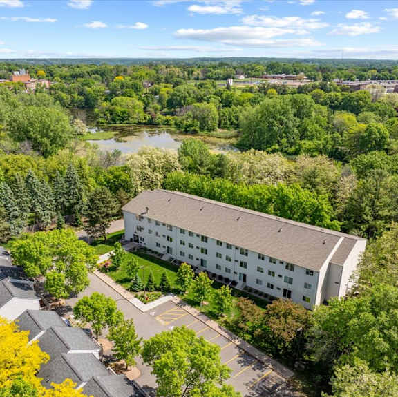 A large white building surrounded by trees and a parking lot.