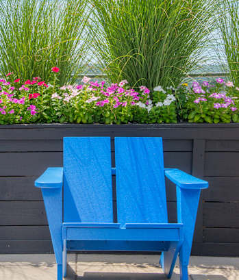 a blue chair sitting in front of a flower garden