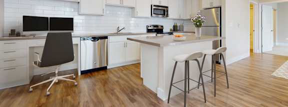 A modern kitchen with white cabinets and a wooden floor.