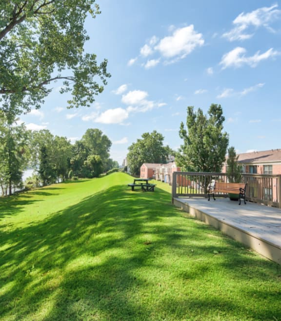 a park with a grassy field next to a building with benches at Brightwaters Apartments, Little Rock, Arkansas
