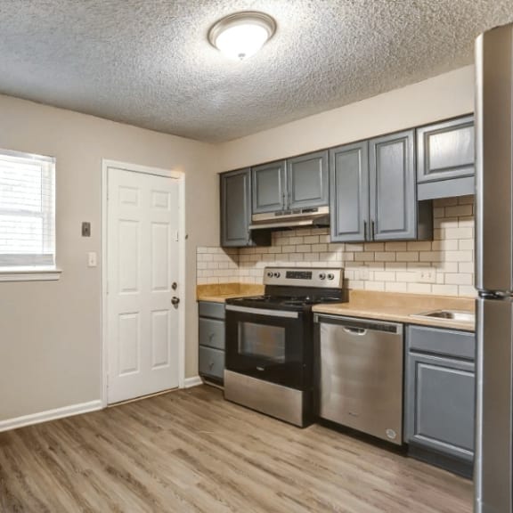 an empty kitchen with stainless steel appliances and gray cabinets at Greenwood Village, Charlotte, NC, 28273