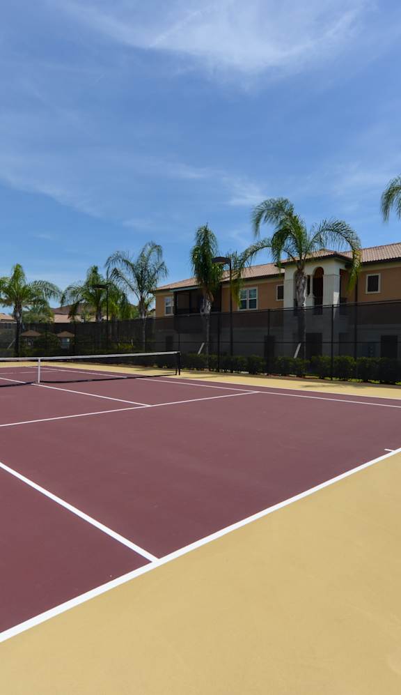 A tennis court with a net and white lines on a sunny day.
