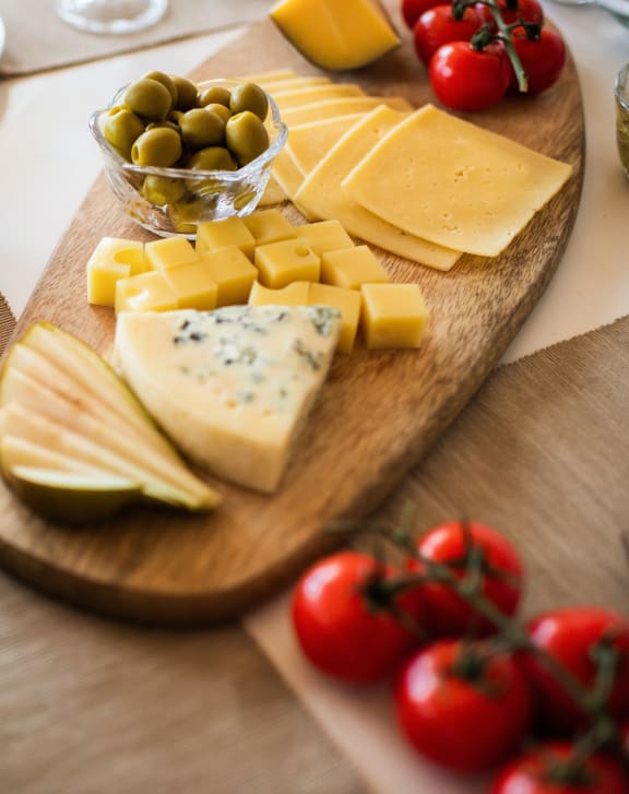 a wooden table topped with a variety of cheese and olives