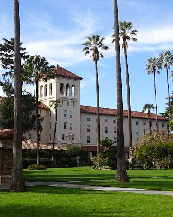 A building with a tower and palm trees in front of it.