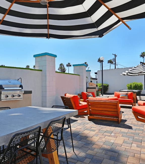 A patio with a table and chairs under a striped umbrella.