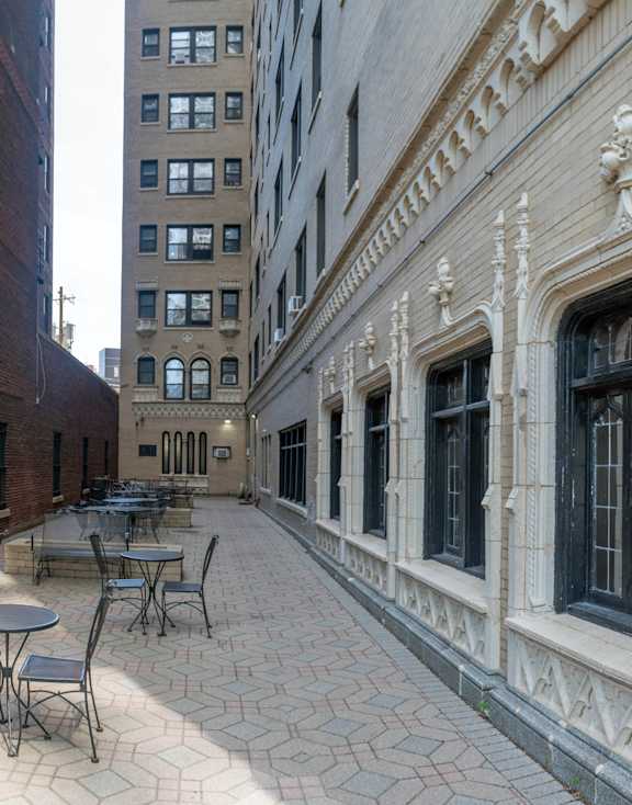 A patio with tables and chairs is surrounded by buildings.