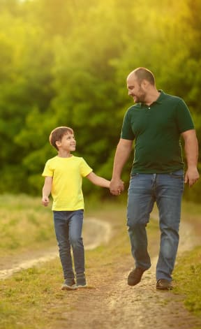 a man and a child walking down a dirt road