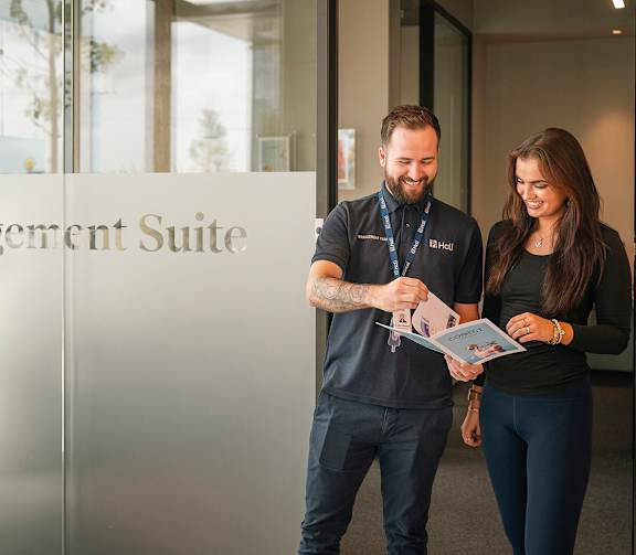 Two people standing in front of a glass door with Management Suite written on it.