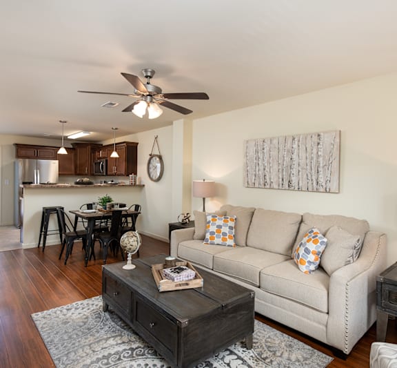A living room with a couch, coffee table, and a ceiling fan.