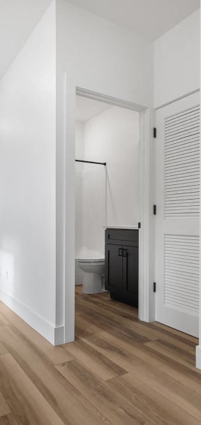 a living room with white walls and a door to a bathroom