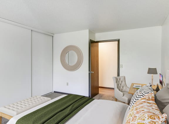 a bedroom with a bed and a chair and a door to a closet