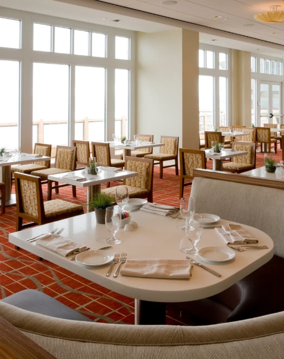 A restaurant with tables set for dining with a view of the ocean.