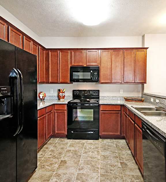 A kitchen with black appliances and brown cabinets.
