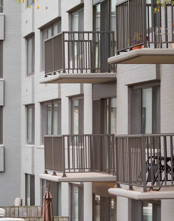 a row of apartment buildings with tables and chairs in front of a tree