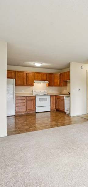 A kitchen with white appliances and wooden cabinets.
