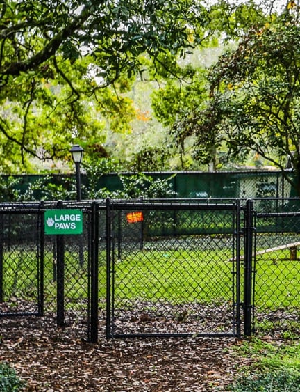 a park with a sign and a fence and trees at The Arbor Walk Apartments, Tampa, FL 33617
