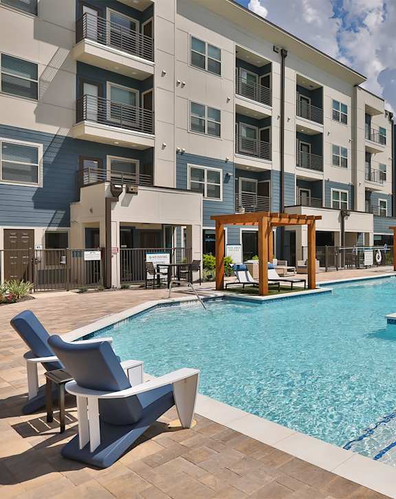 A swimming pool surrounded by chairs and buildings.