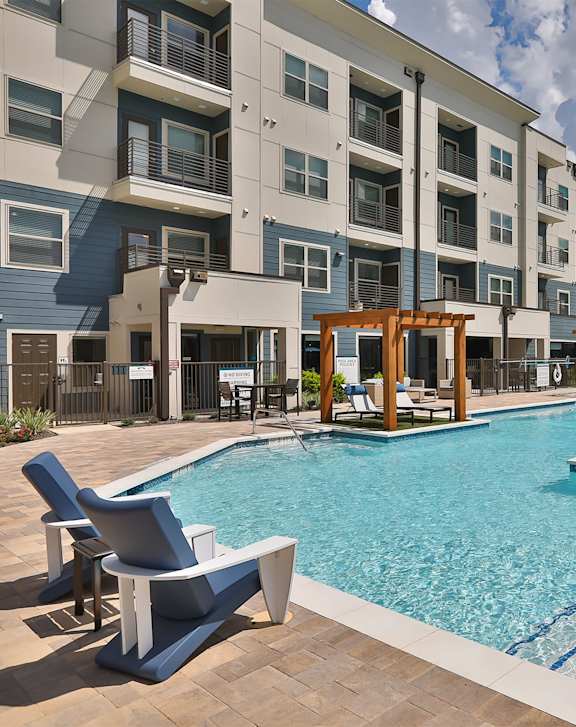 A swimming pool surrounded by chairs and buildings.