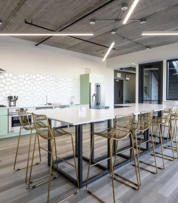 a kitchen with a long white table and chairs