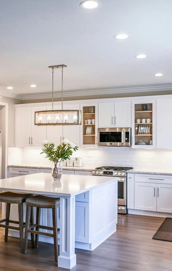 a large kitchen with white cabinets and a white island