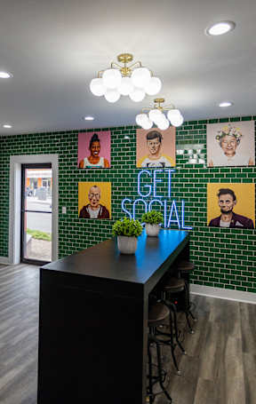 A room with a black counter and a green tiled wall with pictures and the words "GET SOCIAL" on it.
