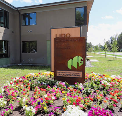 a building with a sign in front of a bed of flowers