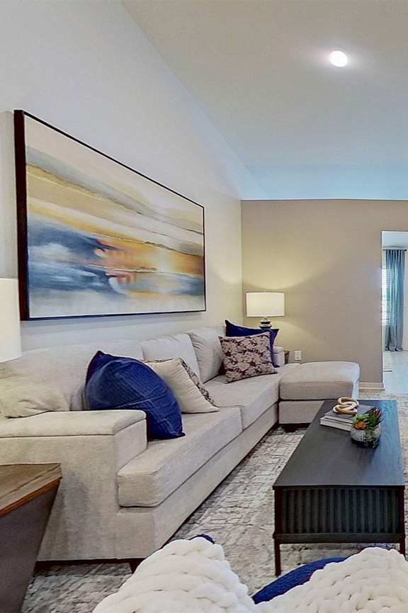 A spacious living room with a couch, coffee table, and a painting on the wall.