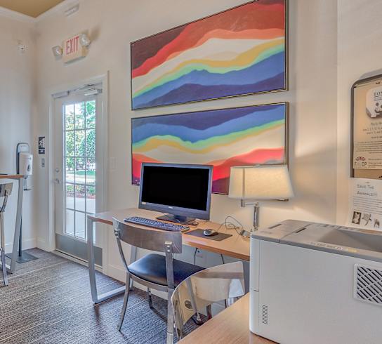 A room with a desk, chairs, and a computer.