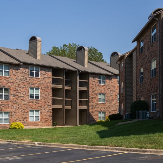 A parking lot with cars parked in front of an apartment building at Foxfire Apartments.