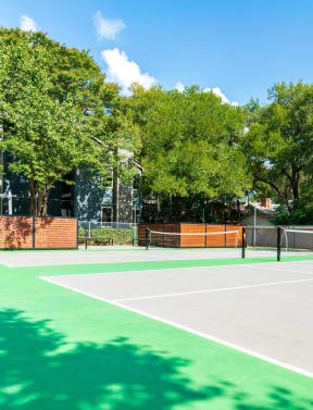 a tennis court with green turf and a fence