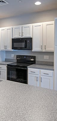 a kitchen with white cabinets and a black stove and refrigerator
