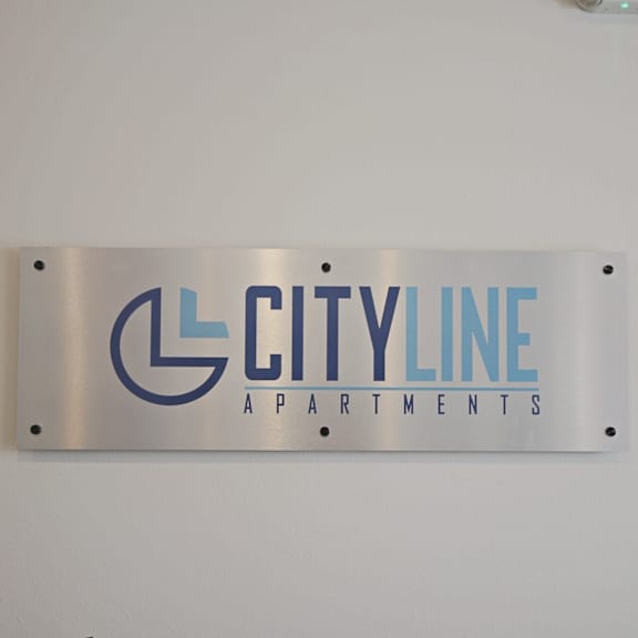 A sign for Cityline Apartments is hanging on a wall.