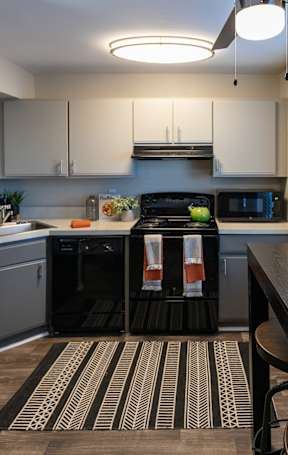A kitchen with a black fridge and a clock on the wall.