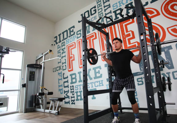 a man lifting weights in a gym with logos on the wall