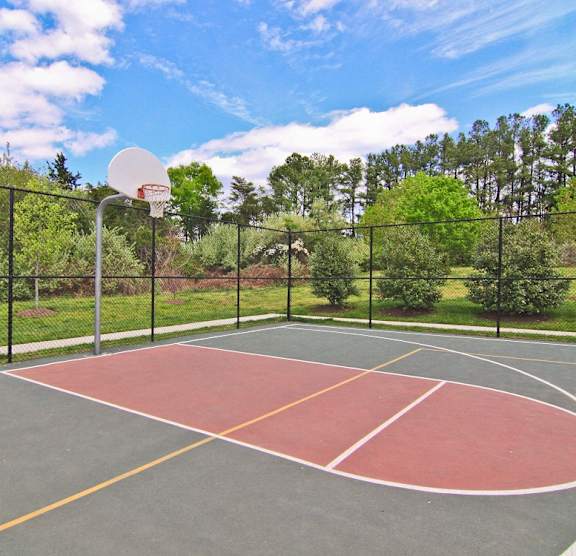 A basketball court with a basketball hoop and a fence surrounding it. at Barrington Park Apartments, Manassas